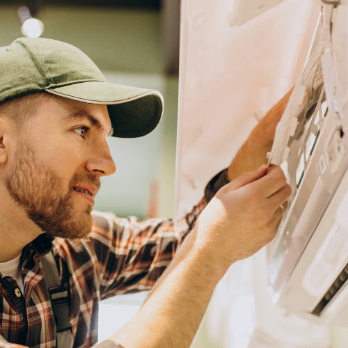 A man dressed in a plaid shirt and hat, representing an HVAC technician, prepares for his tasks.